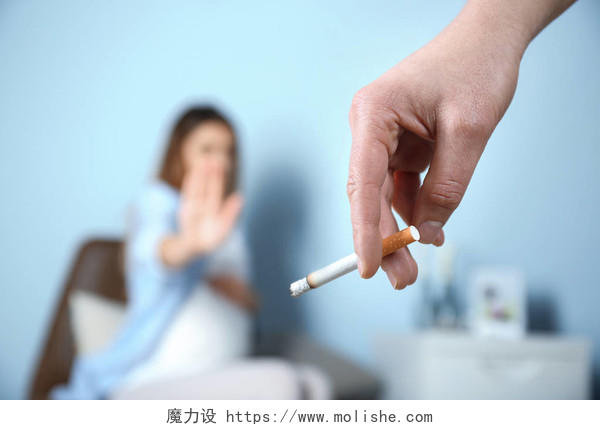 香烟与背景模糊怀孕女人的手